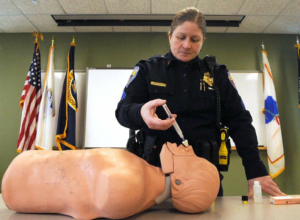 A police officer demonstrates the proper administration of Naloxone, a drug that can reverse a deadly heroine overdose.