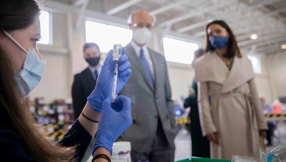 Pa. Gov. Tom Wolf and Acting Secretary of Health Alison Beam watch as Penn State Health vaccination clinic staff fill syringes of the COVID-19 vaccine.