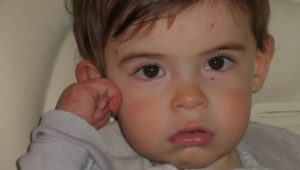 child with fist near his ear
