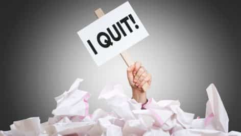 I quit placard in hand with crumpled paper pile