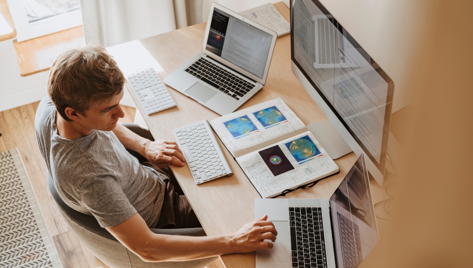 Man working with three computers.