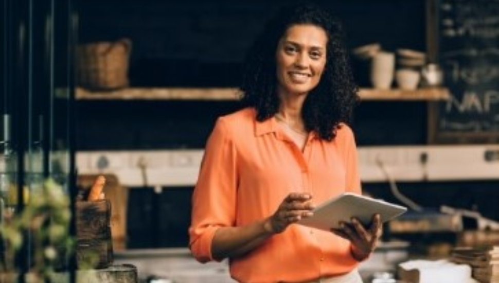 A woman smiling holding an iPad with a checklist.