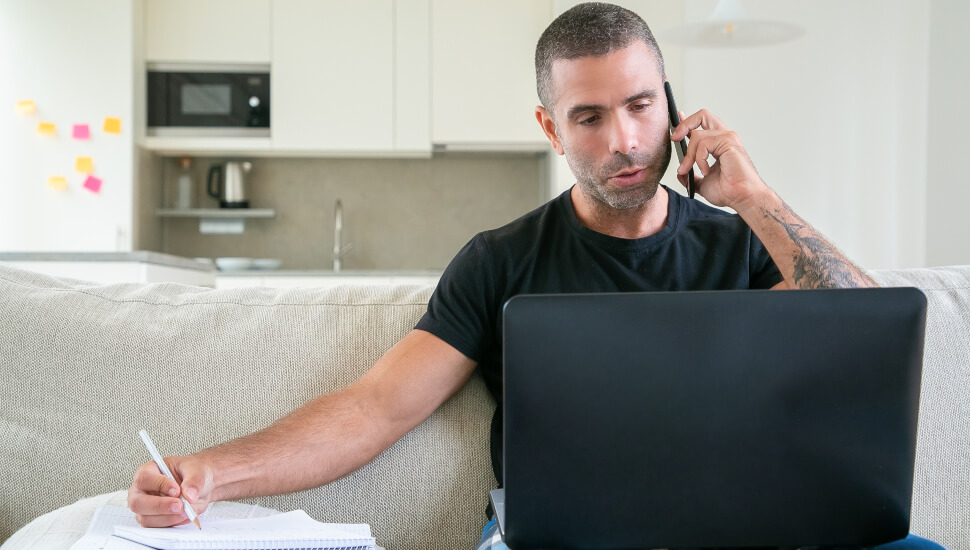 Man taking talking on the phone notes on the couch