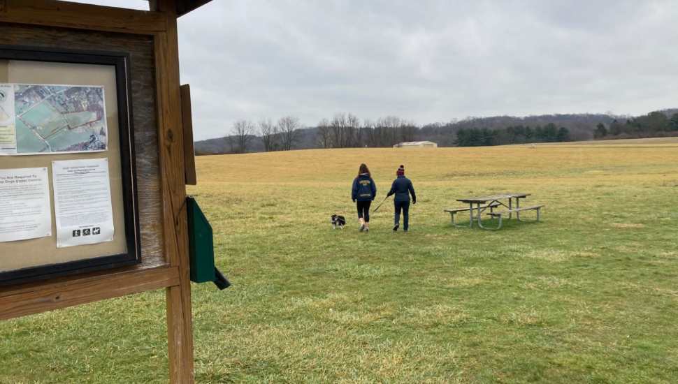 two people one dog in a park