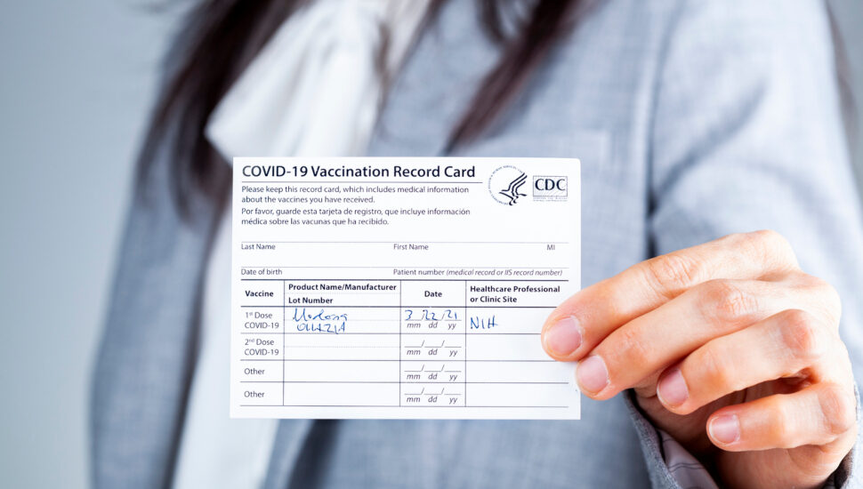 Woman Holding Vaccination Record Card