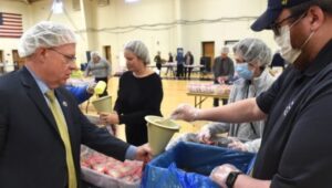 Neumann University President Dr. Chris Domes working with volunteers to fill food packages for Ukrainian refugees.