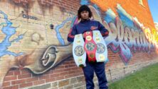 boy poses with championship belts