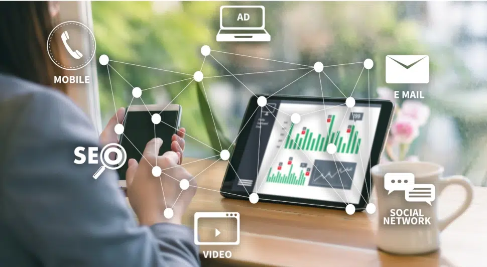 A man at his desk in front of a laptop surrounded by marketing images.