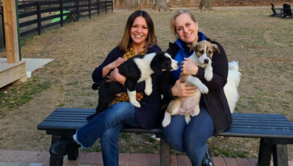 two women smiling with two dogs