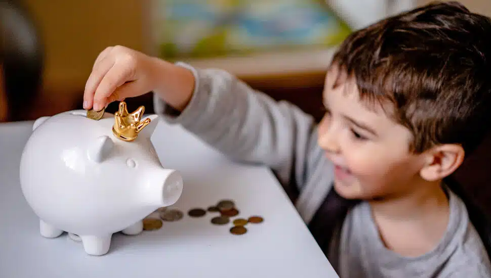 Boy putting pennies in his piggy bank