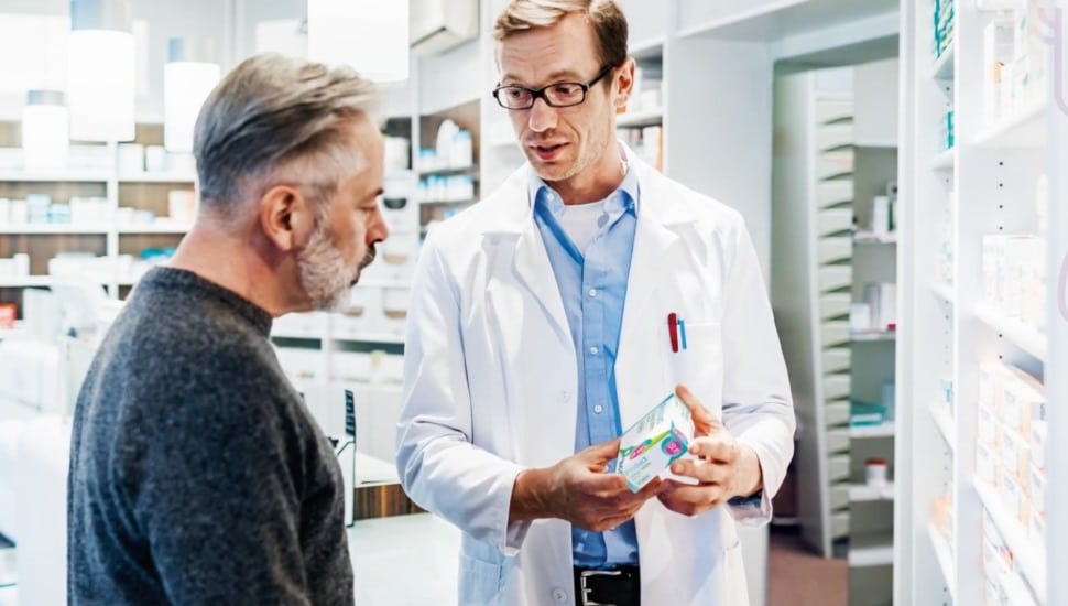 pharmacist showing man medication options