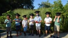 Seven children wearing graduation caps, the graduating class of the Arc of Chester County preschool