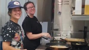 Laura Vernola and Amanda Barros cooking in the kitchen