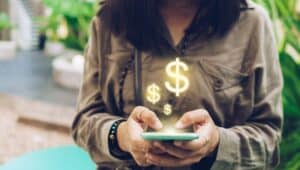 woman holds phone with dollar signs popping up