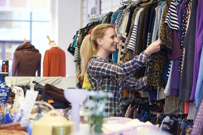 Female Shopper In Thrift Store Looking At Clothes