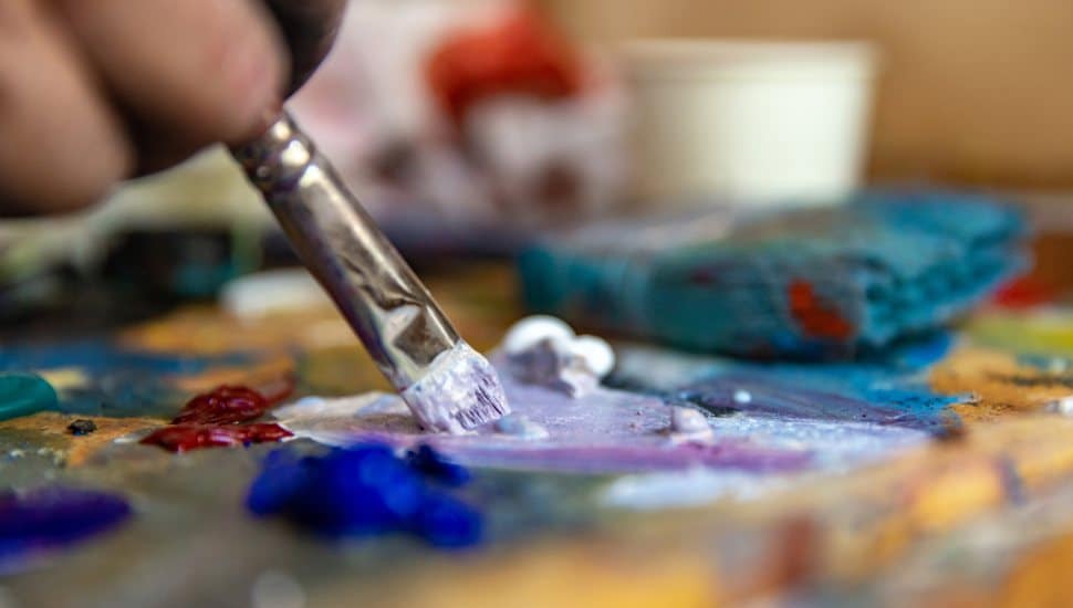person dabbing paintbrush on pallet