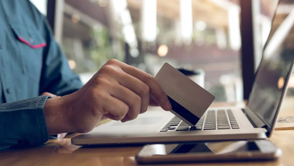 person holding credit card while on laptop