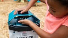 Child uses a hand sanitizer station before playing at a playground.
