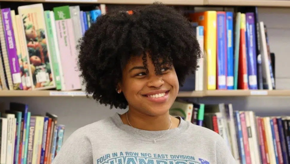 girl smiling with bookshelves behind her