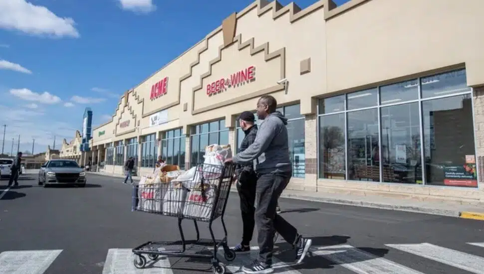 Exterior of Acme, people in foreground with carts in parking lot