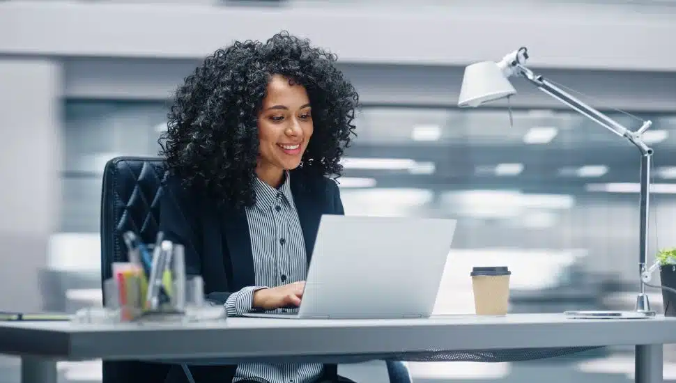 Modern Office: Businesswoman Sitting at Her Desk Working on a Laptop Computer.