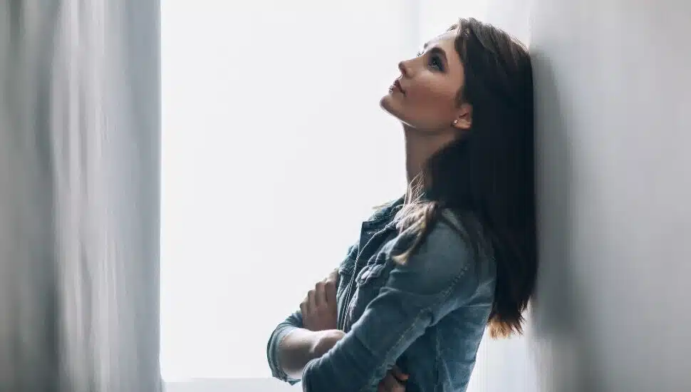 vulnerable woman leaning against a wall.