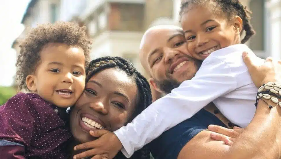 A mom, dad and two kids share a group hug