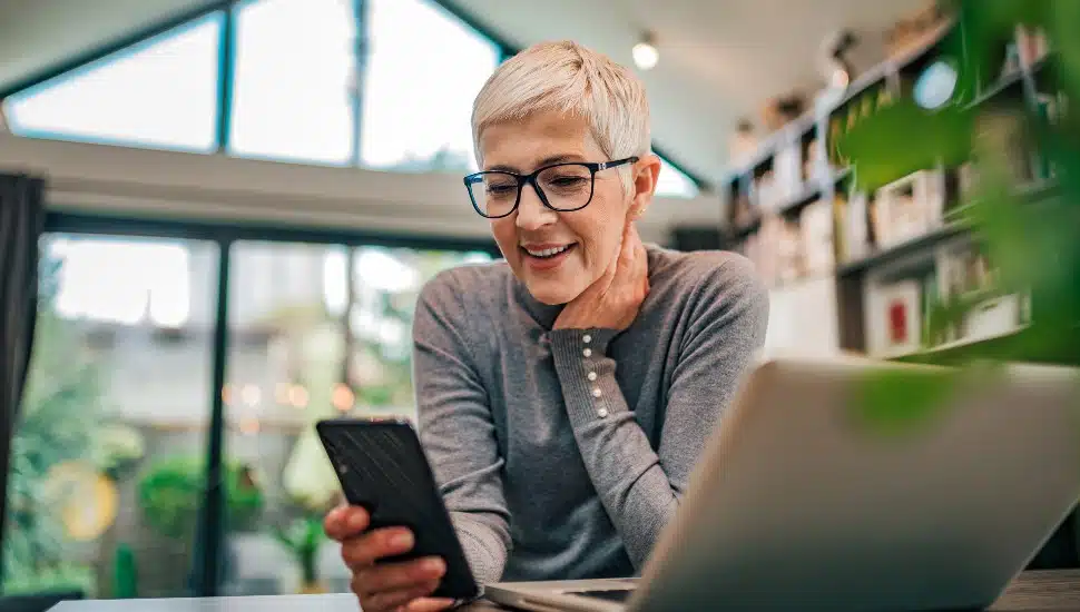 businesswoman using smart phone at home office, working remotely