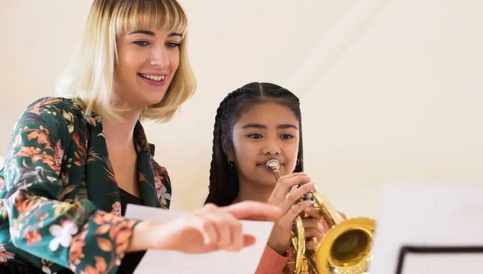 Teacher Helping Female Student To Play Trumpet In Music Lesson
