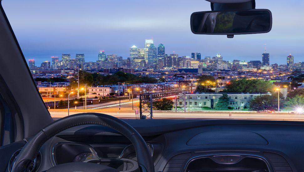 Looking through a car windshield with view of Philadelphia skyline at night
