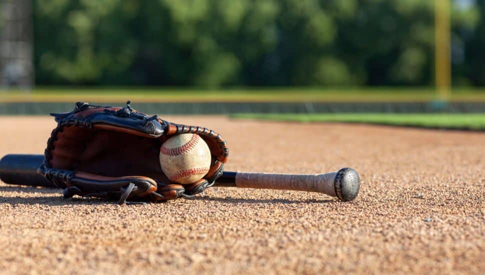 baseball in mitt on dirt with baseball bat