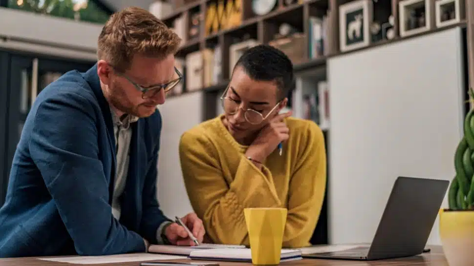 A mentor and a small business owner look over plans as the mentor offers guidance about the woman's small business.