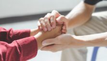 Close-up of psychologist or psychiatrist sitting and holding hands palm of patient for encouragement.