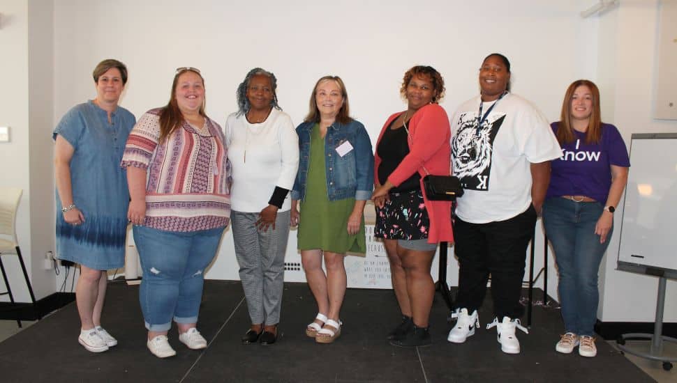 Benchmark Federal Credit Union’s Rebecca Worthington presents the award to 2022 award winner Haley Ricci, accompanied by runners-up Renee Washington and Deborah Willet. They’re joined by Belinda’s daughters Tanya and Michelle, and Ranery Figueroa-Torres from Health Partner Plans.