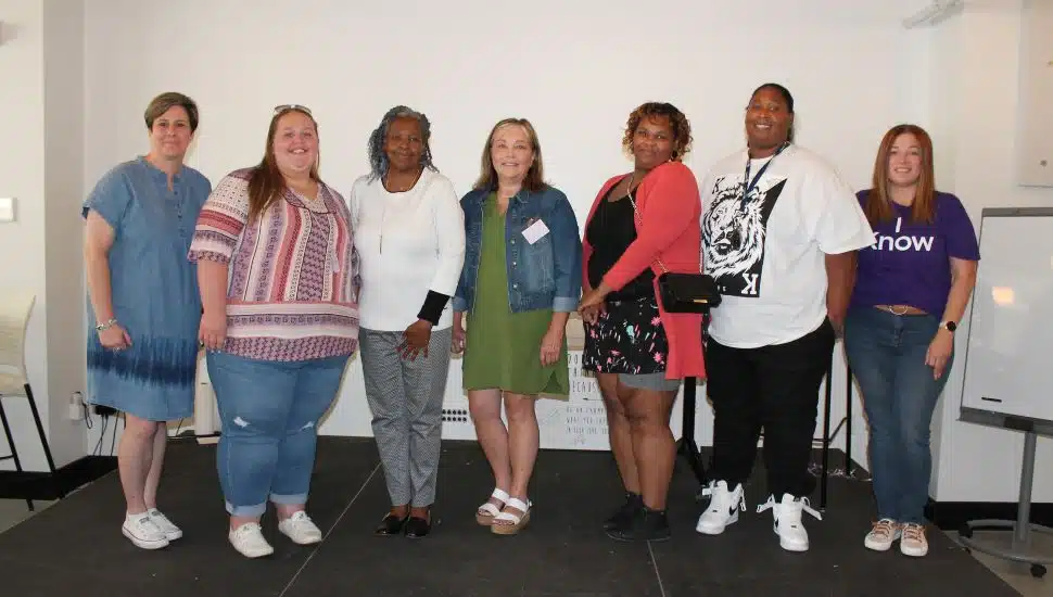 Benchmark Federal Credit Union’s Rebecca Worthington presents the award to 2022 award winner Haley Ricci, accompanied by runners-up Renee Washington and Deborah Willet. They’re joined by Belinda’s daughters Tanya and Michelle, and Ranery Figueroa-Torres from Health Partner Plans.