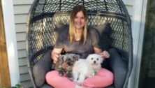 Kristin Blunk is seated comfortably on the patio, joined by her two dogs. She is a behavioral health technician