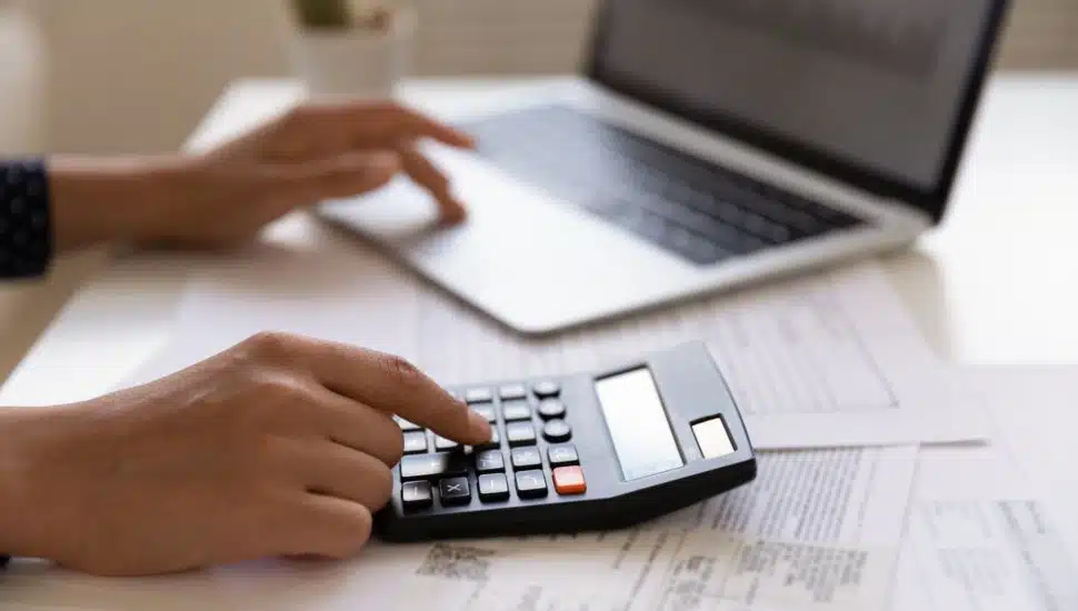 person typing on calculator and laptop