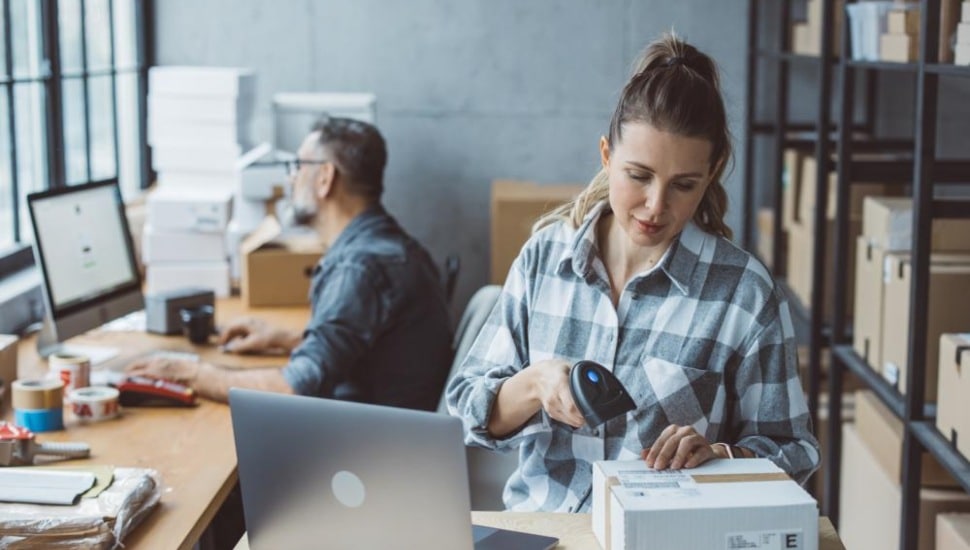 A man and woman at computers in an office running an E-Commerce business.