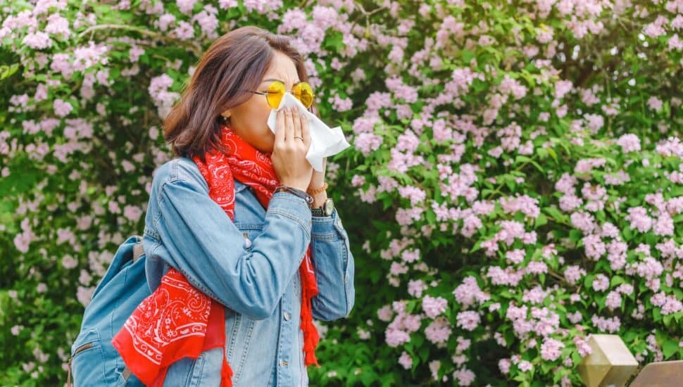 woman sneezing outside, spring allergies