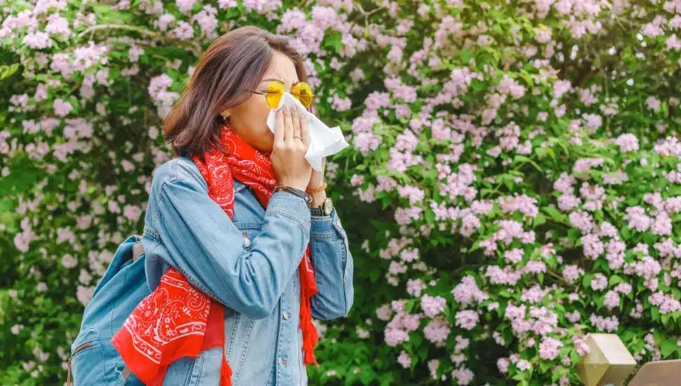 woman sneezing outside, spring allergies