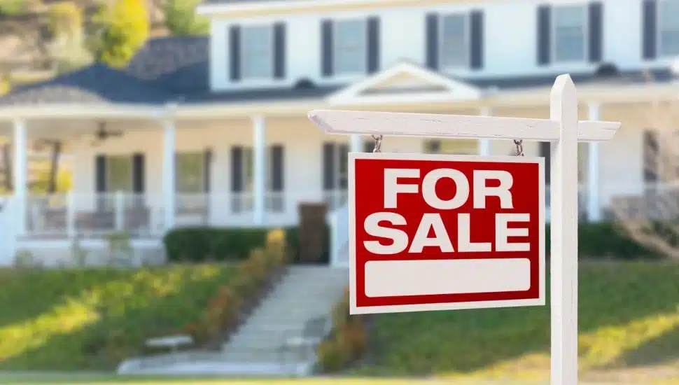 Home For Sale Real Estate Sign in Front of Beautiful New House.