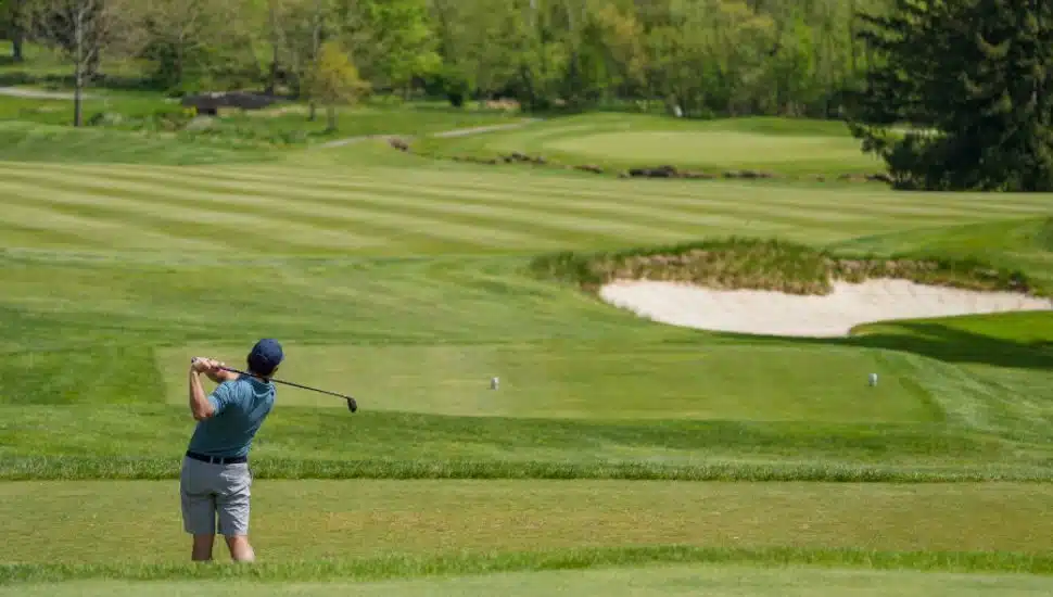 person swinging golf club on course
