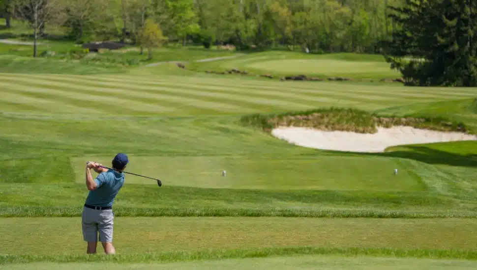 person swinging golf club on course