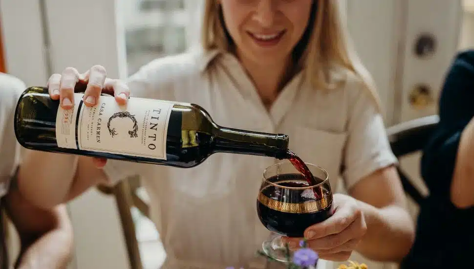 woman pouring Casa Carmen wine into glass