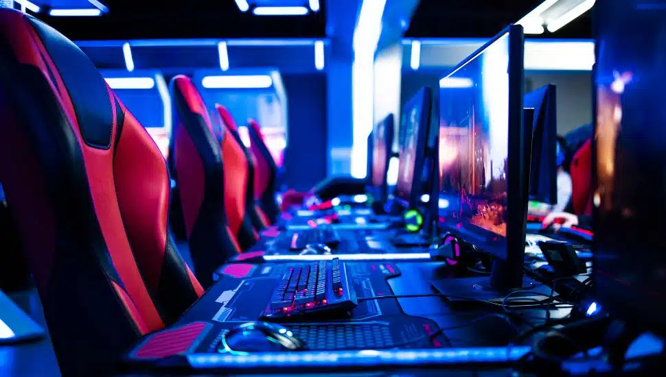 Game room interior with modern ambient lights and powerful super computers, consoles, keyboards for playing video games. Entertaining industry.