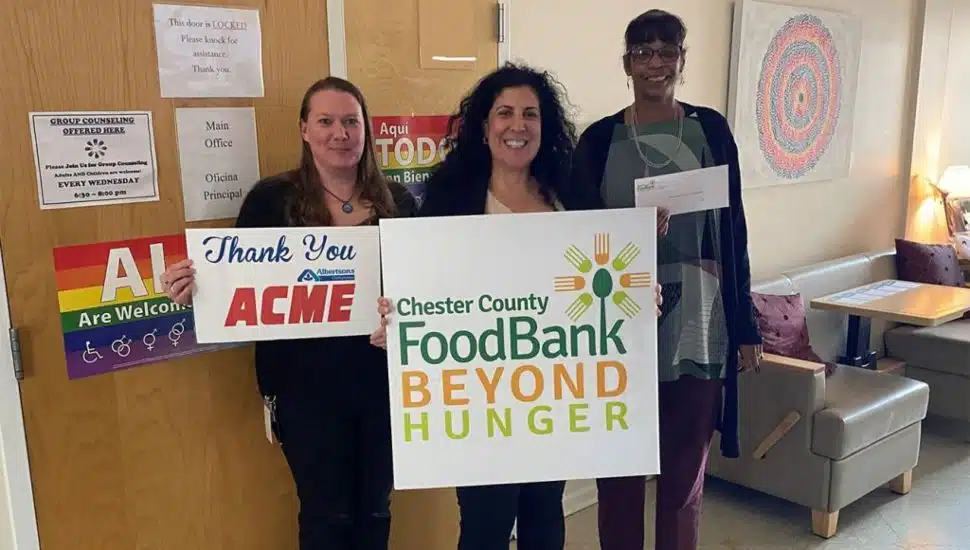 three people stand with ACME and CCFB posters