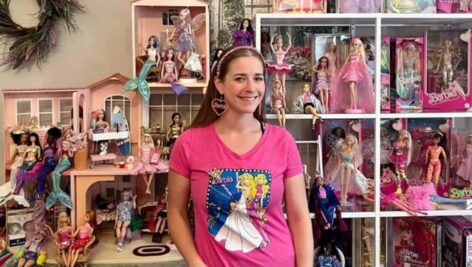 Ilana Volain standing in front of her Barbie collection.