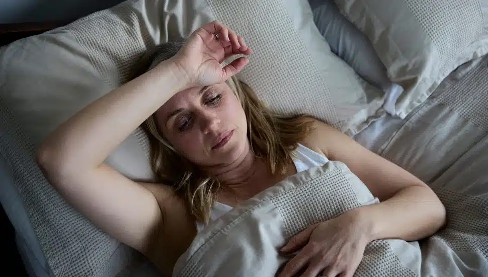 woman getting hot flashes while laying in bed