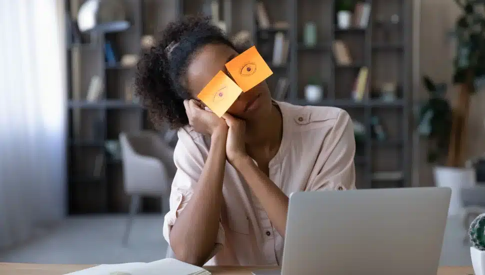 Exhausted young African American woman work on computer at home office, have sticker pads on eyes feel sleepy.