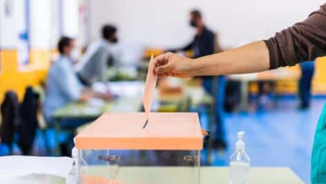 person voting by putting envelope into box